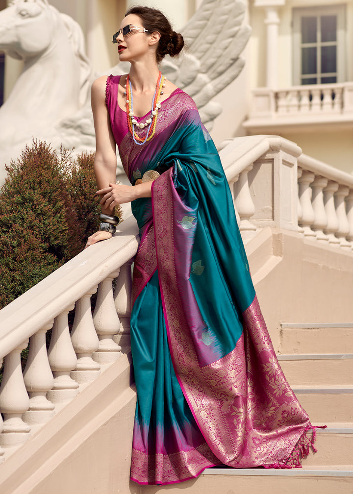 A woman posing by a staircase wearing a blue and pink silk saree with zari work and a contrast pallu.